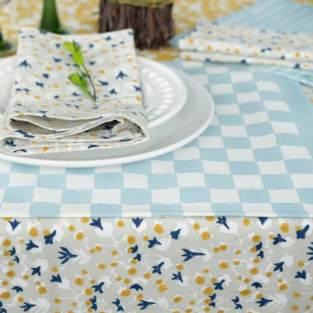 A table set with white dishes on blue and white block placemat, and Japanese wood block print Anna Blue Dijon napkins and table cloth