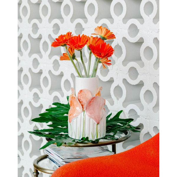 Abigails Handmade Red Wildflower Vase with pink accents on a leafy tray and metal table, geometric white wall behind.