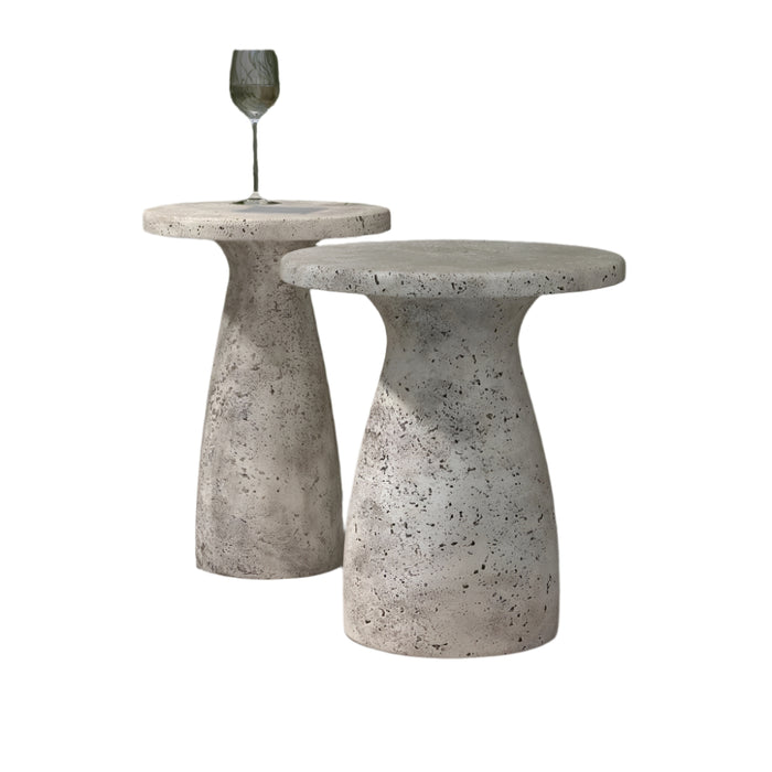 Two rust-colored Collins Concrete Accent Tables by Classic Home sit poolside, framed by tall green grass in the background.