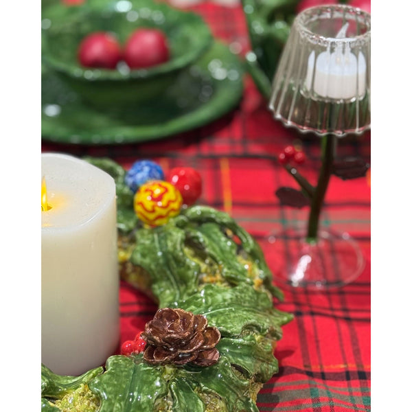 Decorative table setting with candles, green plates, and a red plaid tablecloth.