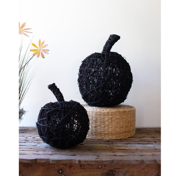Kalalou Black Painted Twig Pumpkins (set of 2) rest on a rustic wooden table and round woven stool.