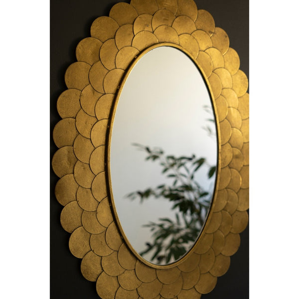 Kalalou's Layered Gold Scallop Framed Mirror reflects a blurred green plant against a dark background.