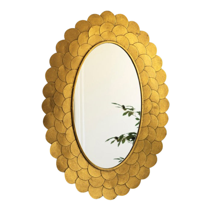 The Layered Gold Scallop Framed Mirror by Kalalou reflects plant leaves, adding chic decor to a dark wall.