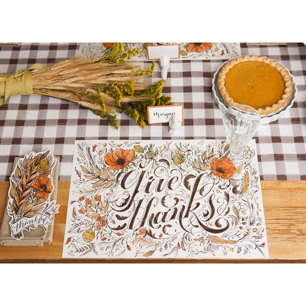 Thanksgiving table with Hester & Cook Give Thanks Paper Placemats, pumpkin pie, wheat bouquet, and holiday decor.