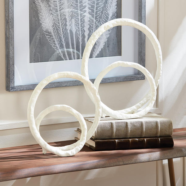 The Eldon White Sculptures (set of 2) by Napa Home & Garden add a touch of modern design to a wooden console table near framed artwork and stacked books.