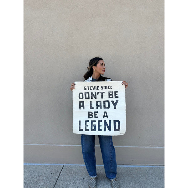 Woman holding Sugarboo & Co. Stevie Said Hand Painted Wall Hanging with the quote, “Don’t be a lady, be a legend.”.
