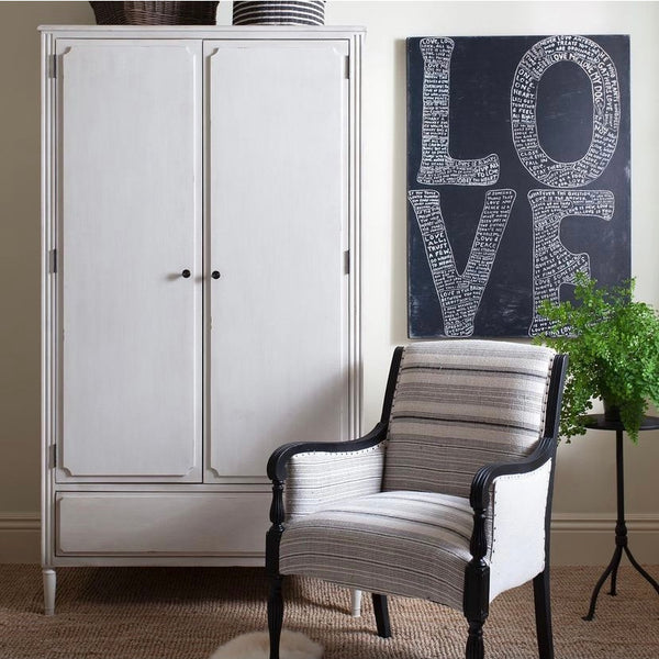 A cozy room featuring a white wardrobe, a striped armchair, a potted plant, and the "L-O-V-E" Gallery Wrapped Canvas Wall Art Print by Sugarboo & Co., showcasing retro-style art on the wall.