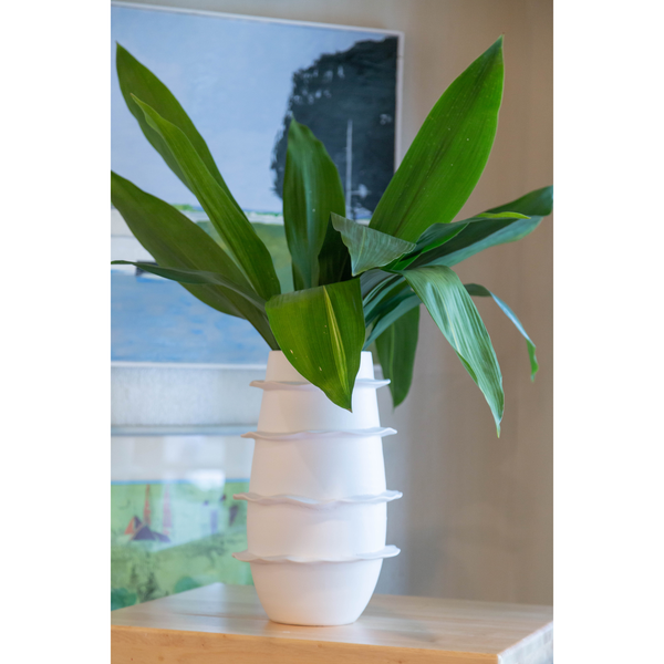 Galaxy Spiral Matte Tall Vase by Abigails, handmade in Italy, featuring large green leaves on a wooden surface with framed pictures blurred in the background.