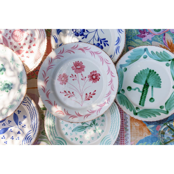 The Casa Nuno Pink Dinner Plates by Abigails, hand-painted with stunning floral designs, rest elegantly on a colorful tablecloth, illuminated by dappled sunlight. Inspired by Portuguese Talavera art, these pieces bring vibrant stories to life with every meal.