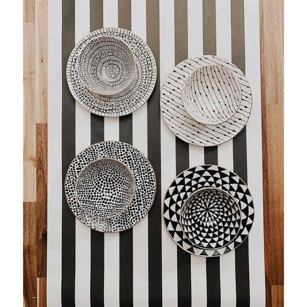 BSEID Stoneware Black + White Bowls with Gold Rim (set of 4) on a striped runner, viewed from above.