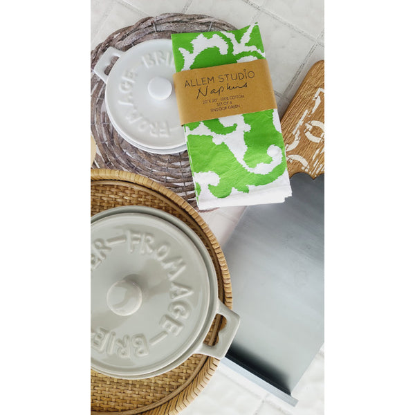 Ceramic dish with lid, Allem Studio's Sindoor Green Screened Napkins (set of 4), and woven placemats on a white surface.