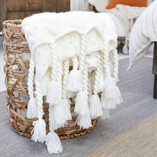 chunky white blanket with pom poms in a basket