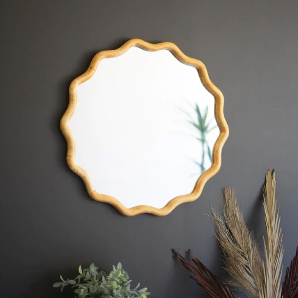 Round mirror with a wooden squiggle frame on a dark wall