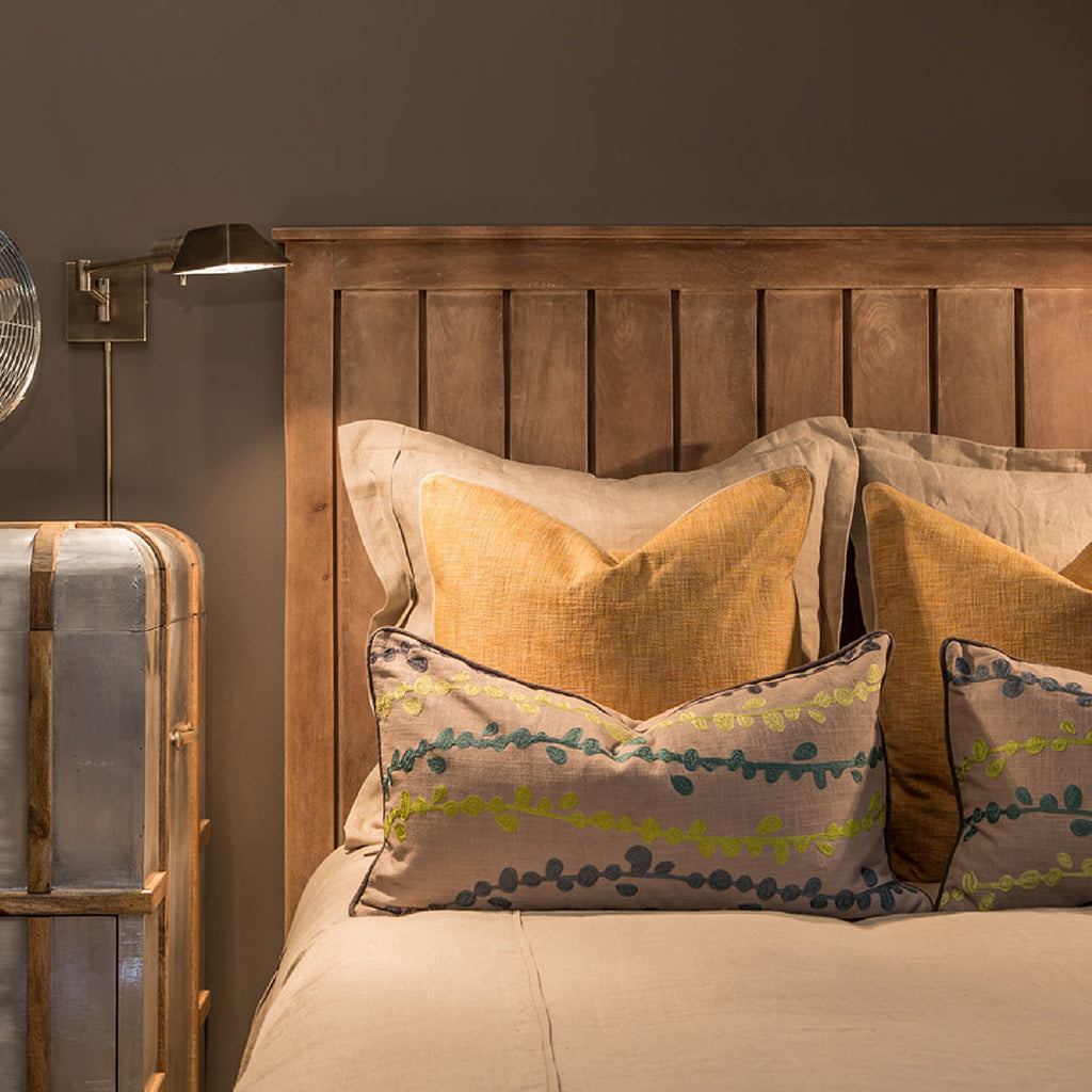 Farmhouse style bed with a wooden headboard and metal wall sconce