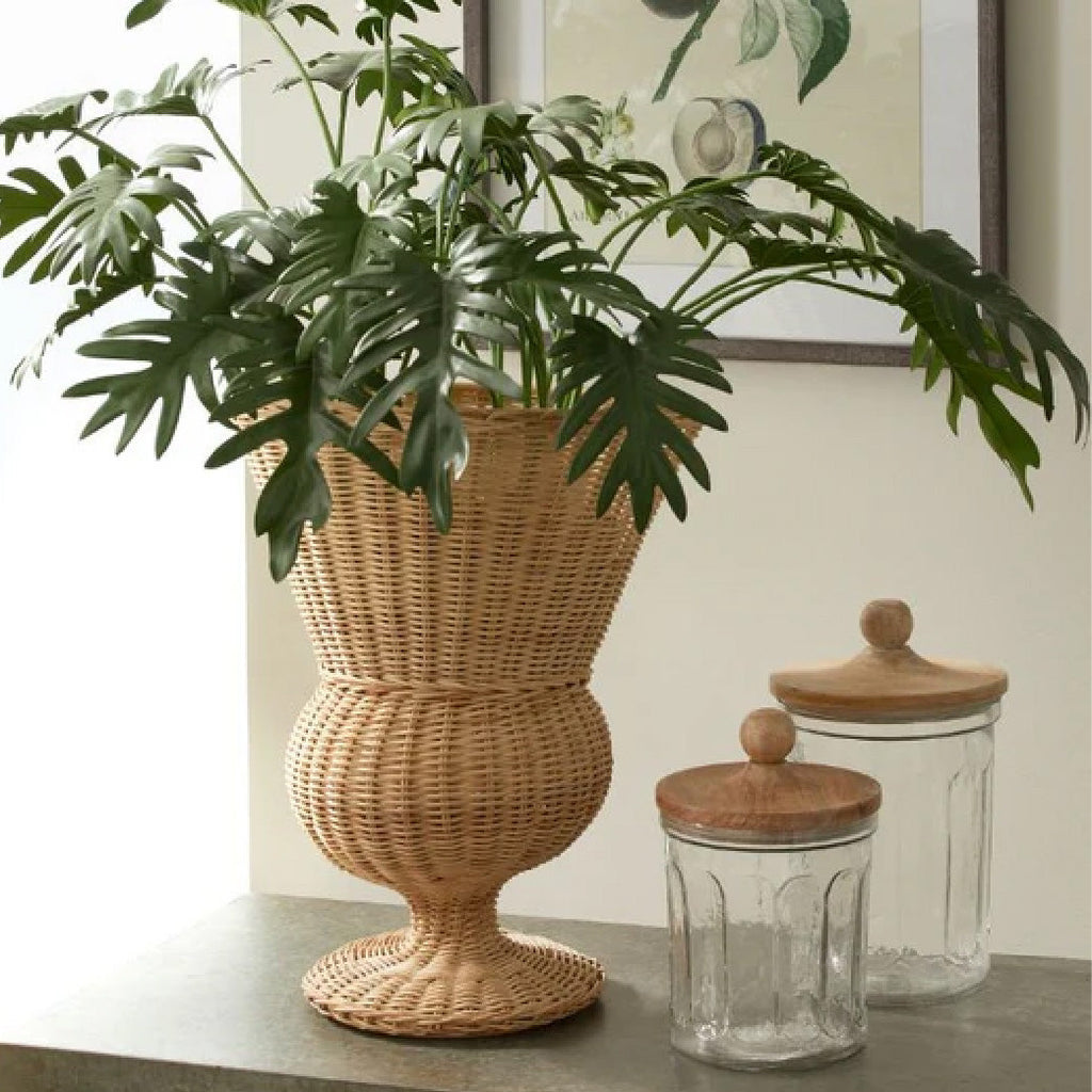 Rattan log holder holding white pom pom throw by a fireplace