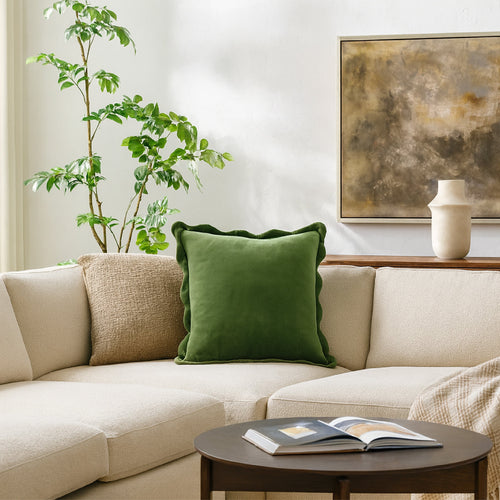 Green velvet pillow on a cream living room sofa