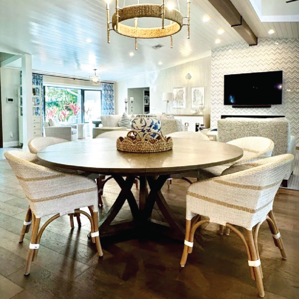 Modern dining area with a round wooden table, six woven chairs, and neutral decor in a bright, open space.