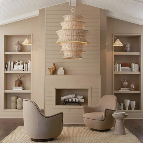 Round wooden dining table with six woven chairs in a bright, modern living space with large windows.