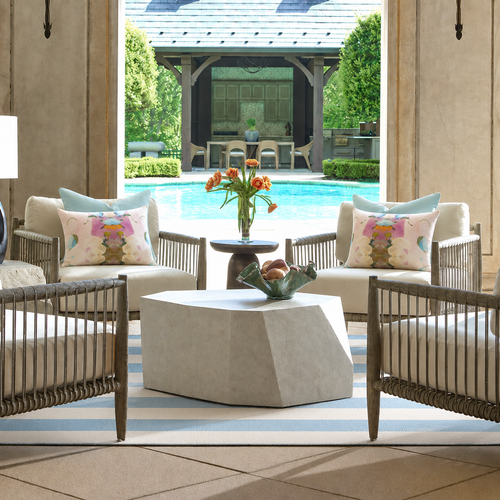 four casual outdoor chairs around a table with a pool in the background