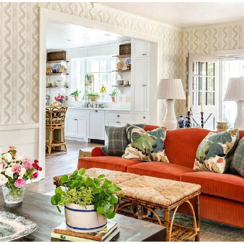 Bamboo console table with lamps and mirror against a patterned green wallpaper backdrop.