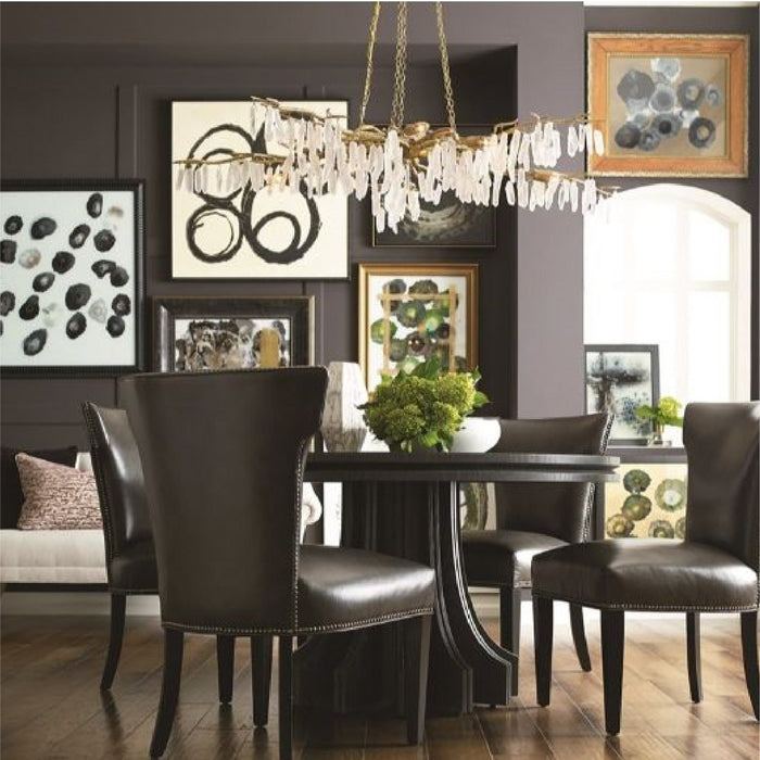 Modern dining room with black chairs, round table, chandelier, and abstract art on dark walls.