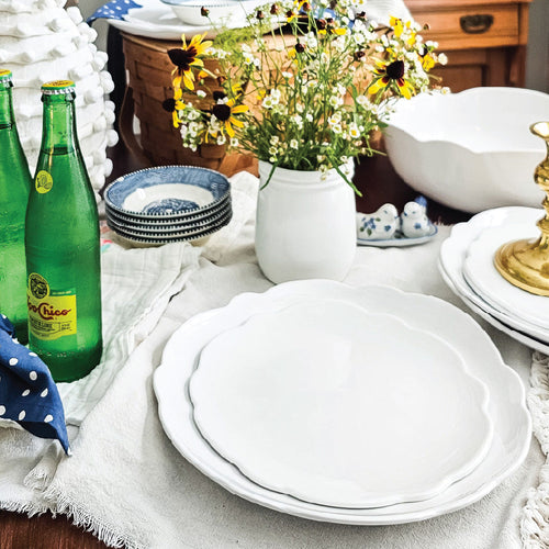 white melamine scalloped dishes on table with cream napkin