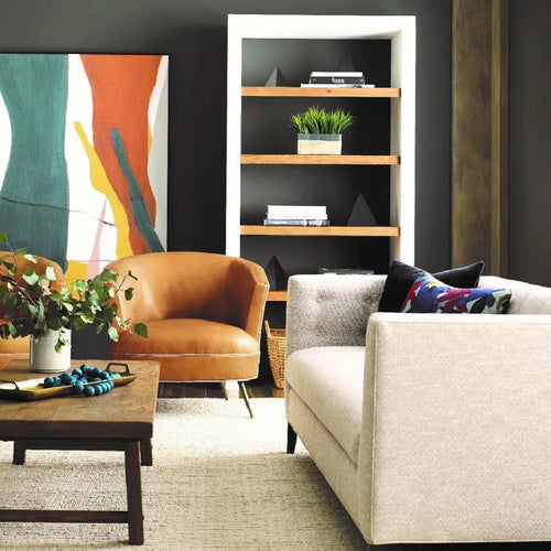 Stylish living room with blue chairs, gray sofa, abstract art, and a white coffee table on a patterned rug.