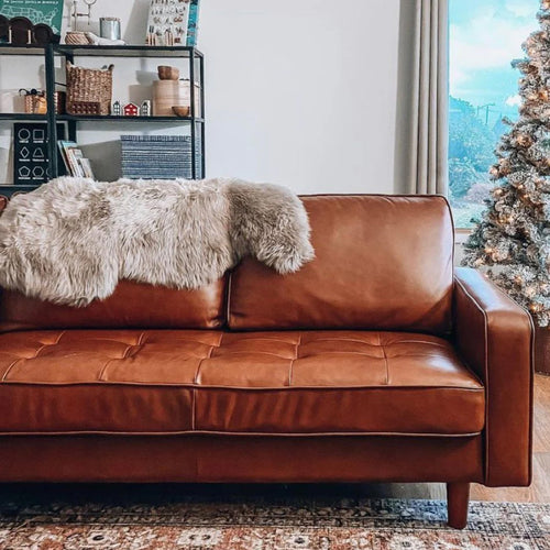 faux fur pelts draped over a camel leather couch 