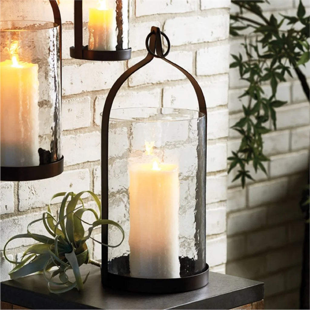 Bronze candle lantern in the shape of a steeple sittng on a black console