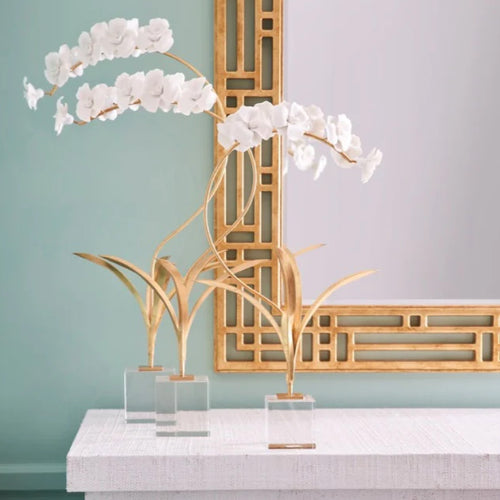 Two handmade matte white porcelain orchidson a dresser with a mirror on the wall