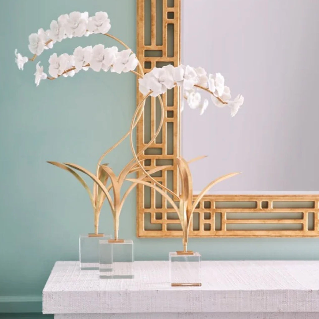 Two handmade matte white porcelain orchidson a dresser with a mirror on the wall