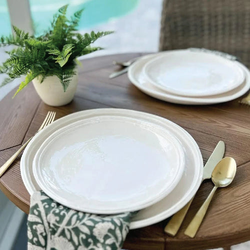 white melamine dishes on table with brass flatware and green floral napkin