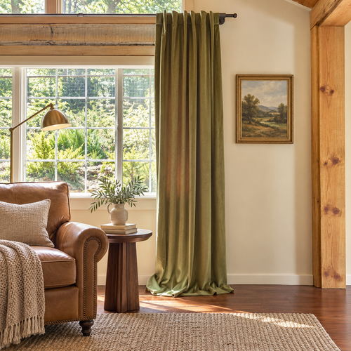 living room green velvet drapes leather sofa book tree
