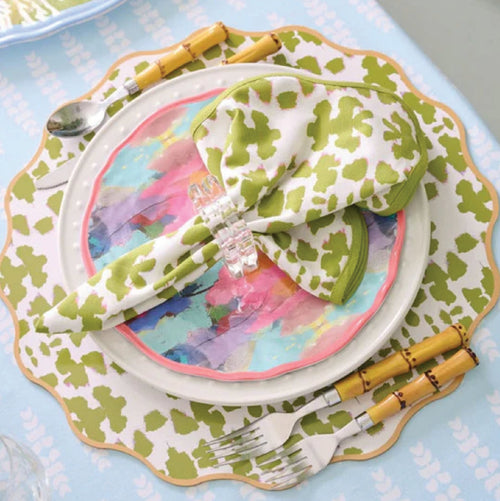 Colorful plate with a green spotted napkin, clear napkin ring, and bamboo-handled cutlery on a table.