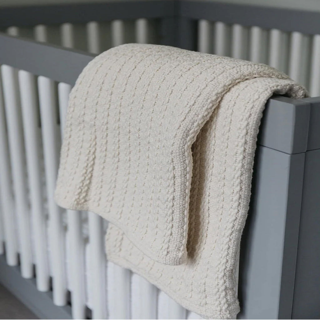gray crib and cream blanket 