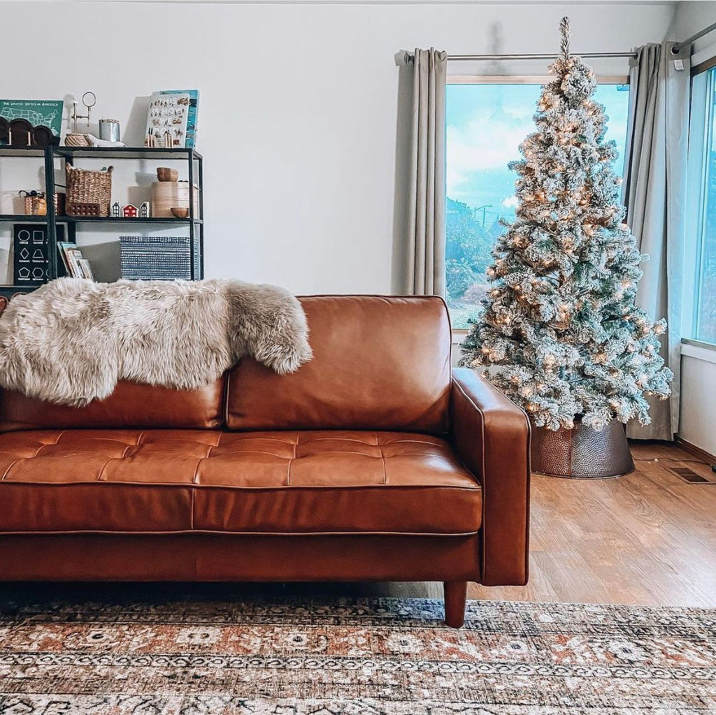 Fur pelt draped over leather sofa with christmas tree in background