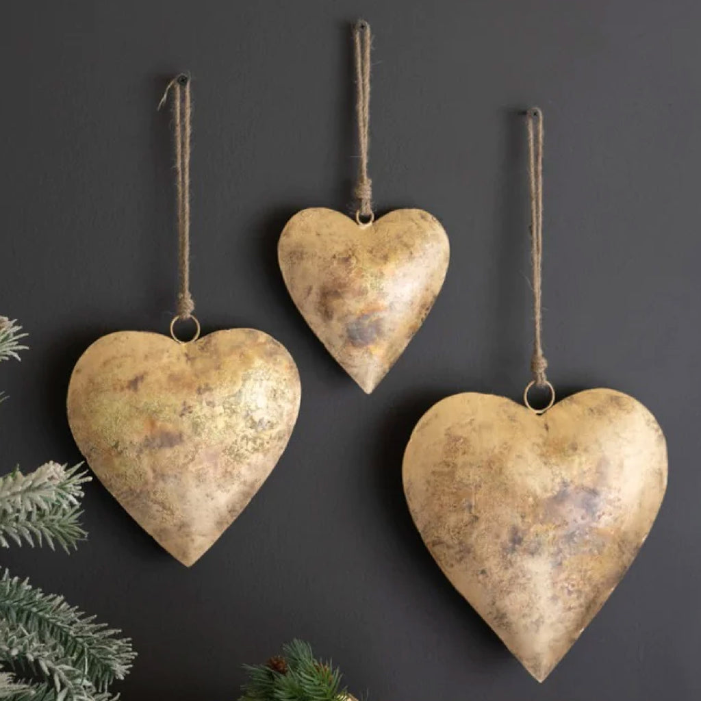 Group of three metal hanging hearts on a dark wall