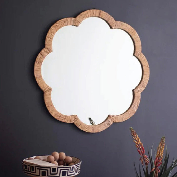 Elegant room decor with a textured mirror, lamp, vase with branches, books, and decorative objects on a shelf.