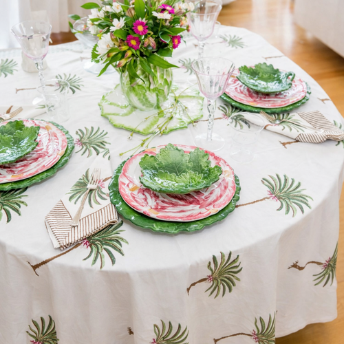 Festive fall table setting with flowers, pumpkins, pinecones, glassware, and colorful plates.