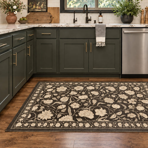 A kitchen with dark green cabinets and a black area rug featuring a cream-colored floral pattern on the wood floor.