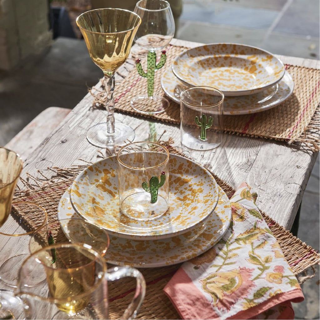 speckled yellow dishes and cactus glass on table setting