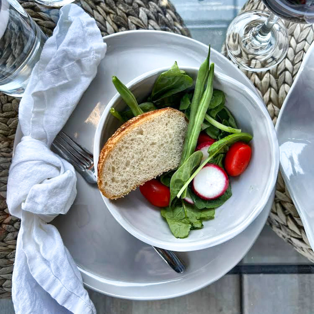 light gray melamine dish and bowl on table with seagrass placemat and white napkin