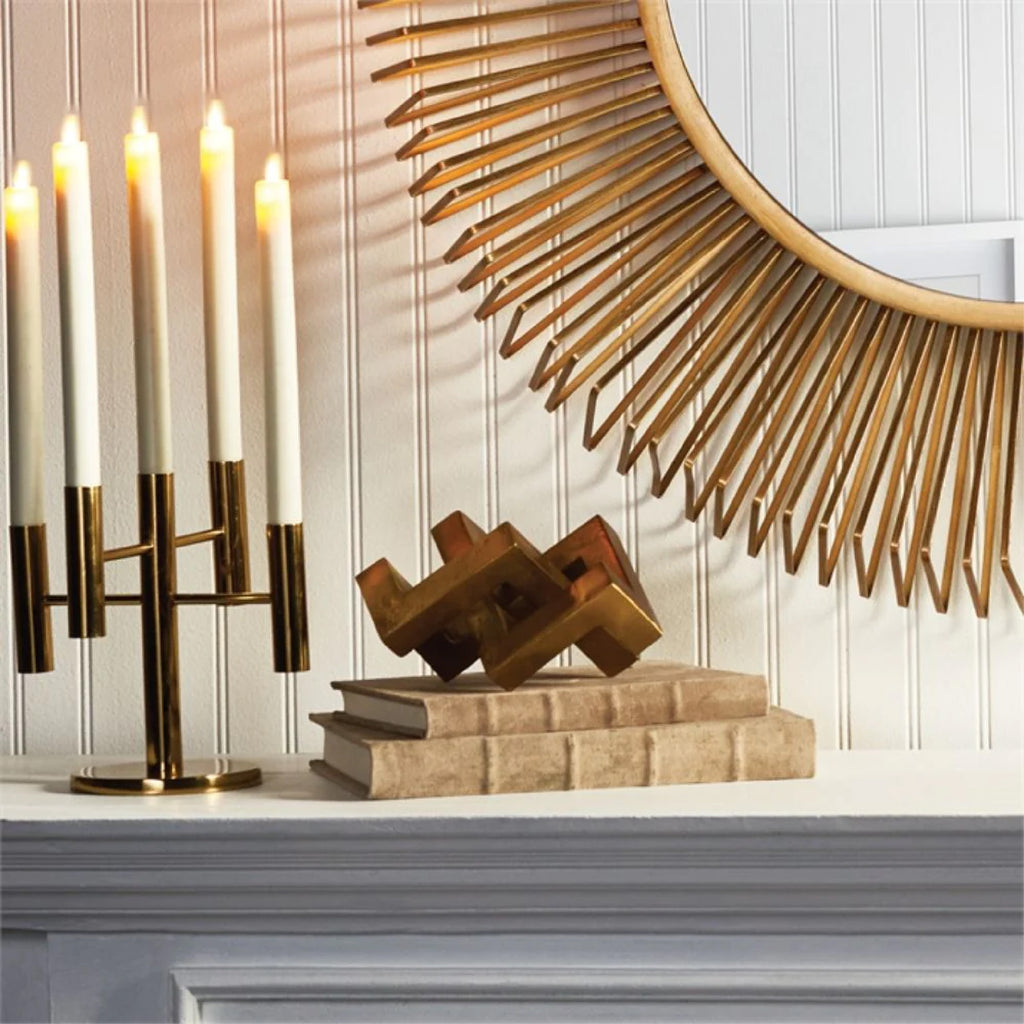 Candles and unique sculpture of gold key atop a mantle