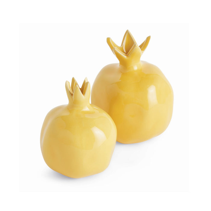 Two yellow ceramic pomegranate-shaped objects on a white background