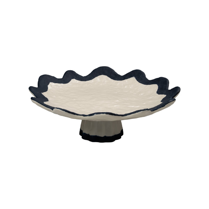 Ceramic footed dish with scalloped edge and navy rim on a white background