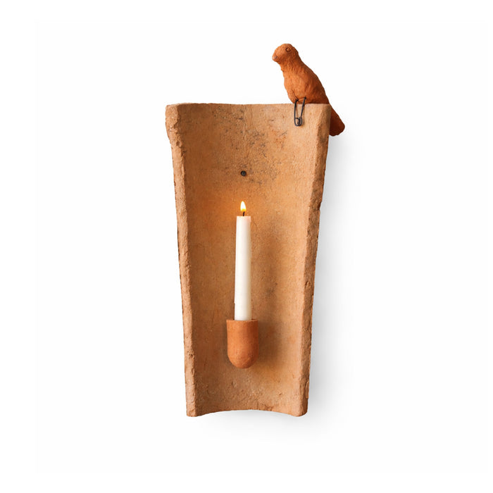 Clay wall sconce with a candle and bird on a white wall