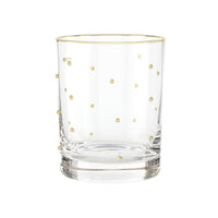 Clear glass tumbler with gold polka dots on a white background
