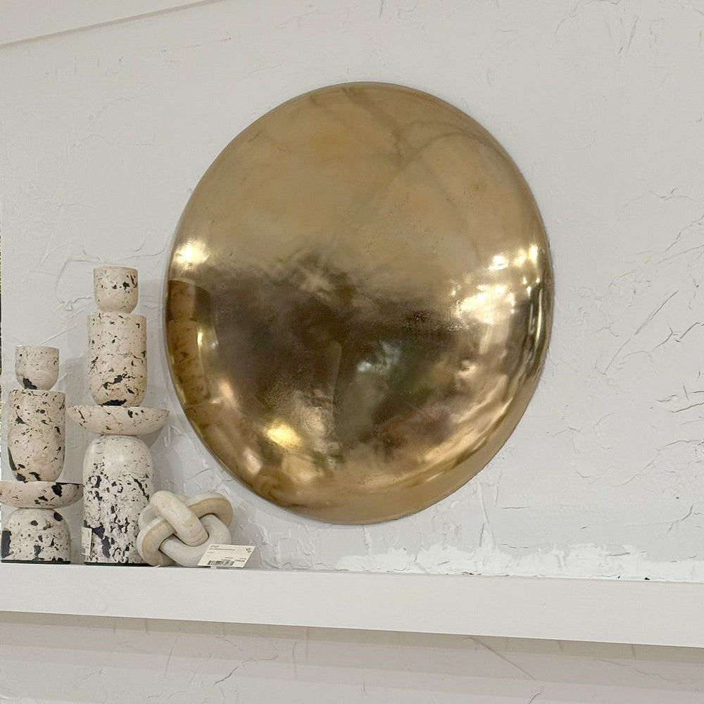 Gold circular object on a textured white surface with small decorative items.