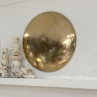 Gold circular object on a textured white surface with small decorative items.