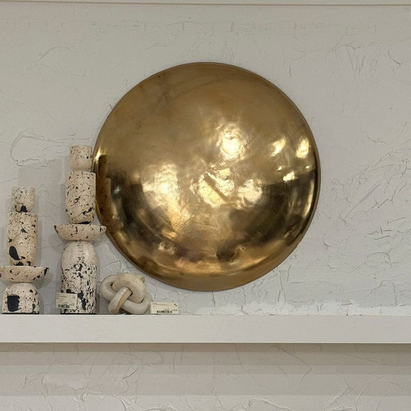 Large brass sphere on a textured white wall